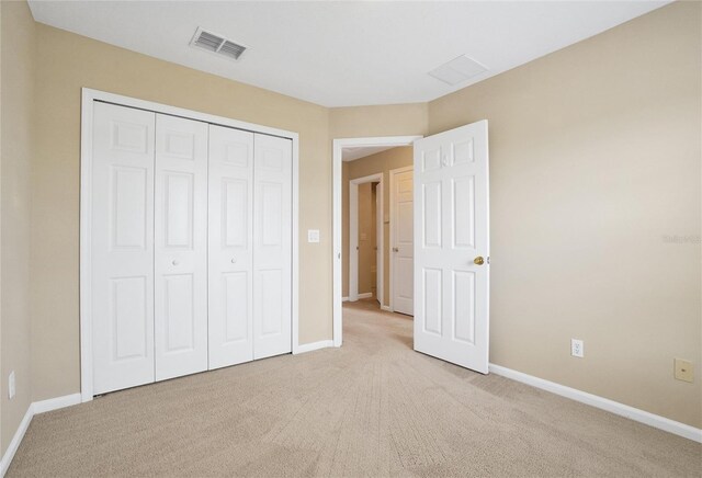 unfurnished bedroom with light colored carpet and a closet