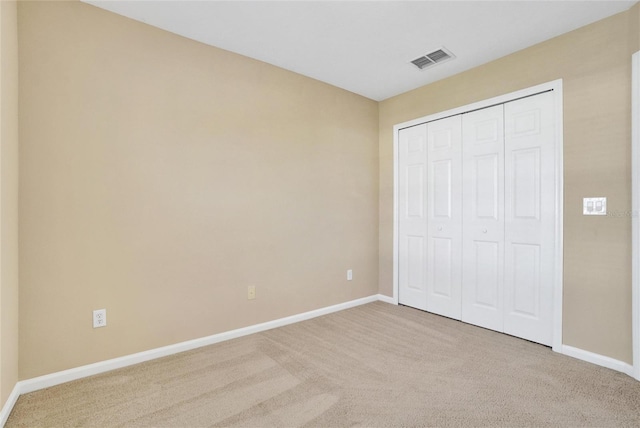 unfurnished bedroom with a closet and light colored carpet