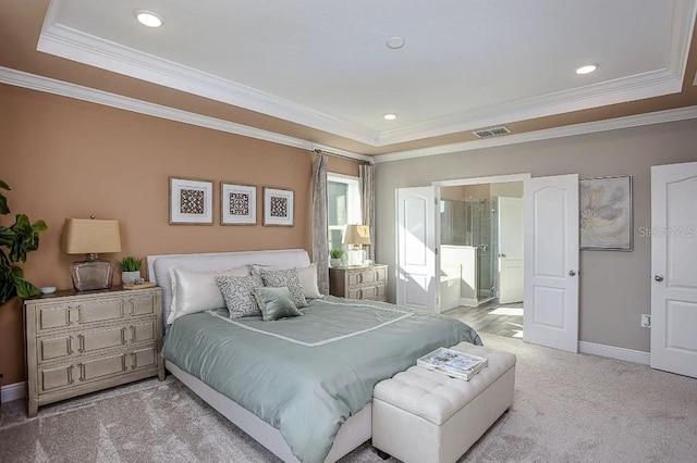 carpeted bedroom with a raised ceiling, crown molding, and ensuite bath