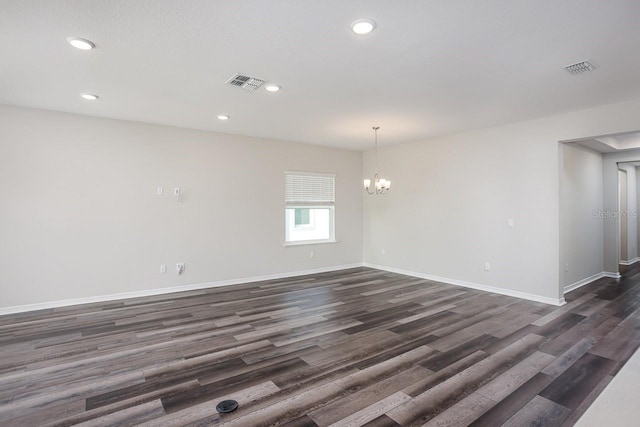 empty room featuring dark hardwood / wood-style floors and a notable chandelier