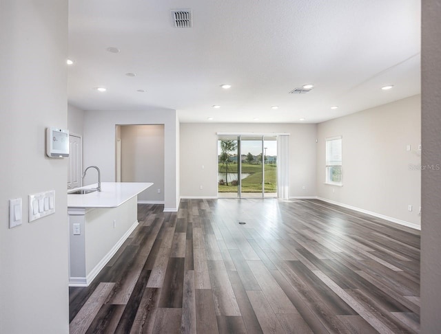 unfurnished living room with dark hardwood / wood-style flooring and sink