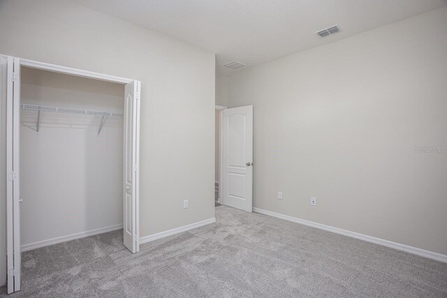 unfurnished bedroom featuring light carpet and a closet