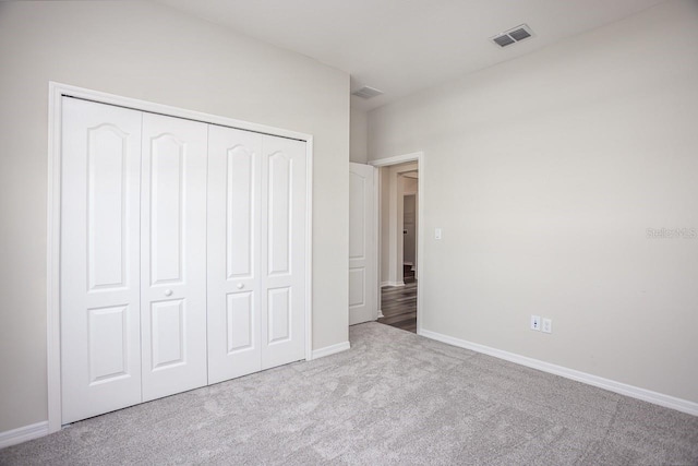 unfurnished bedroom with light colored carpet and a closet