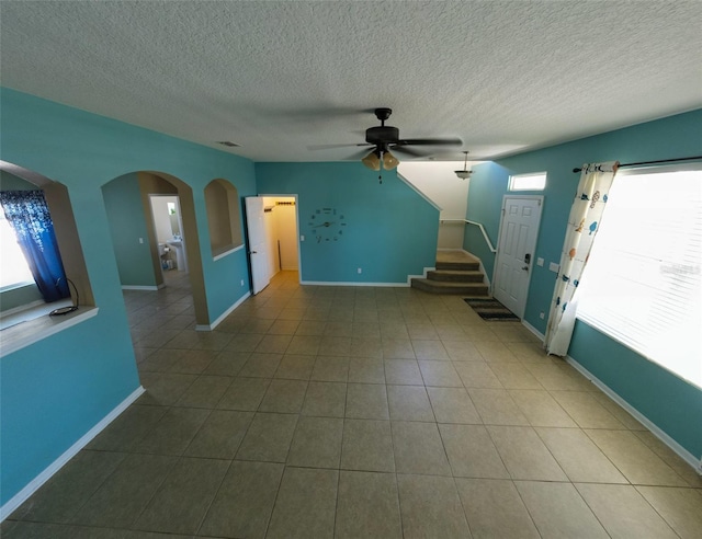 interior space with tile patterned flooring, ceiling fan, and a textured ceiling