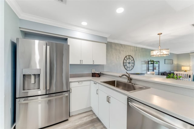 kitchen with sink, white cabinets, ornamental molding, and appliances with stainless steel finishes