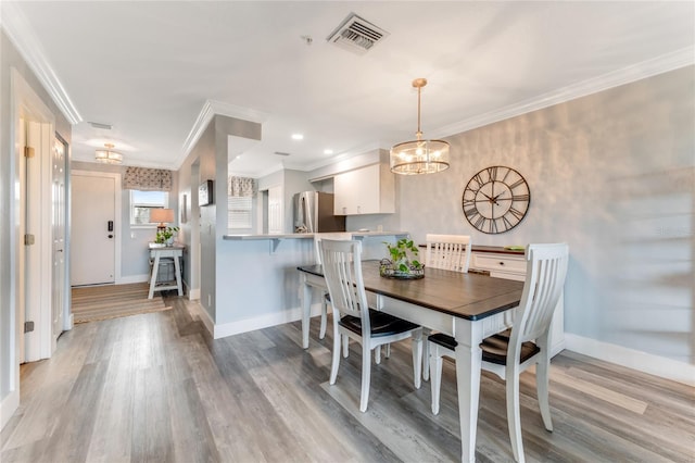 dining space featuring light hardwood / wood-style floors, an inviting chandelier, and crown molding