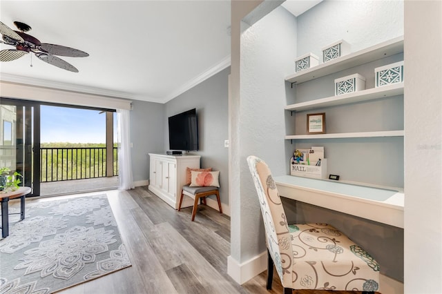 home office with ceiling fan, built in desk, light wood-type flooring, and ornamental molding