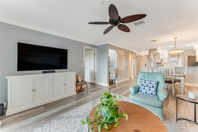 living room with ceiling fan with notable chandelier, light wood-type flooring, and crown molding