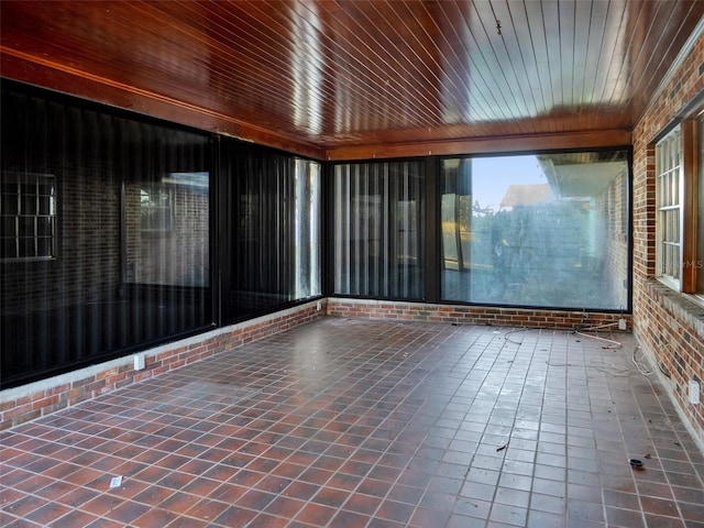 unfurnished room with tile patterned flooring, wood ceiling, and brick wall