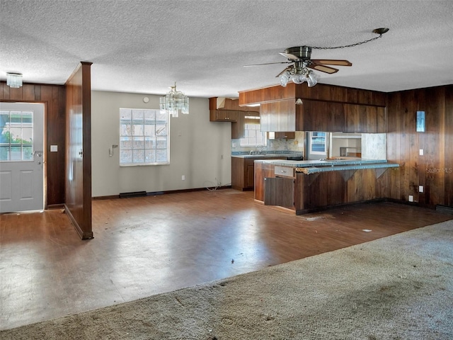 kitchen featuring kitchen peninsula, wooden walls, and a textured ceiling