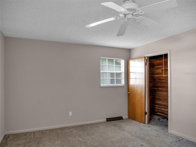 unfurnished bedroom featuring ceiling fan, a closet, light colored carpet, and a textured ceiling