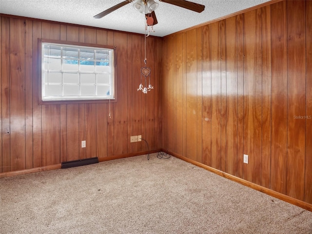 carpeted spare room with ceiling fan, a textured ceiling, and wooden walls