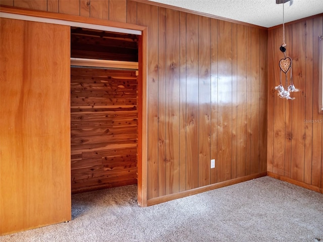 carpeted empty room with wooden walls and a textured ceiling