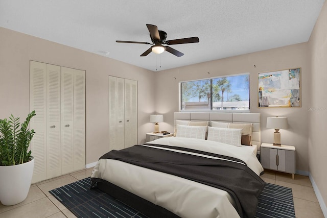 bedroom featuring light tile patterned floors, a textured ceiling, two closets, and ceiling fan