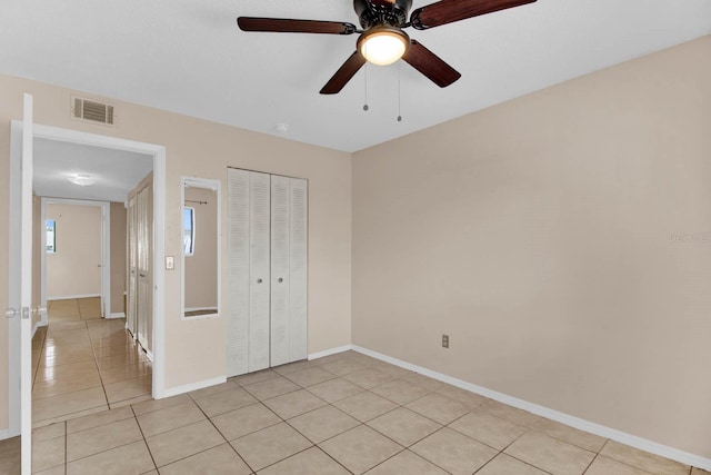 unfurnished bedroom featuring ceiling fan, light tile patterned floors, and a closet