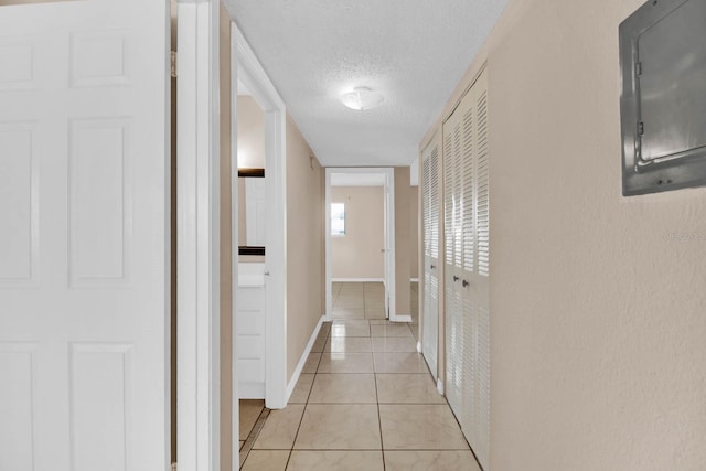 corridor featuring electric panel, light tile patterned flooring, and a textured ceiling