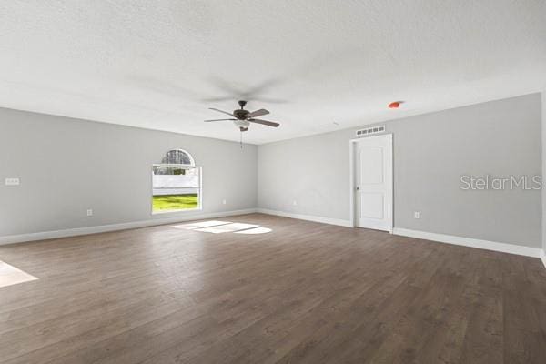 spare room with a textured ceiling, ceiling fan, and dark wood-type flooring