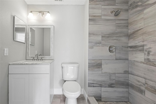 bathroom with vanity, toilet, and tiled shower