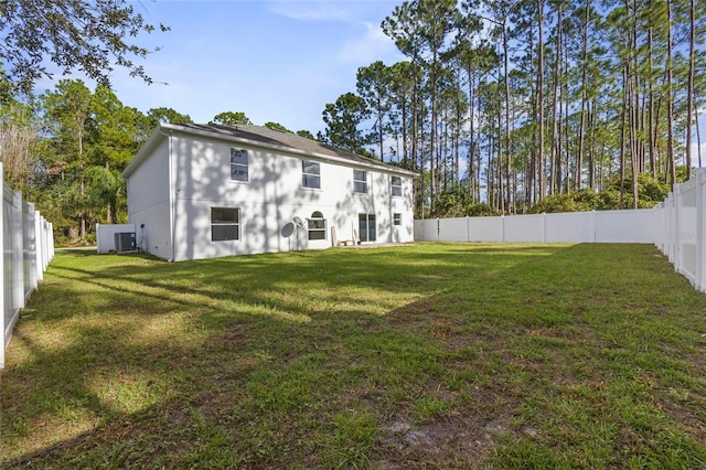 rear view of property with a yard and central AC