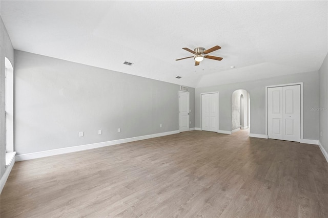 unfurnished room with lofted ceiling, ceiling fan, light hardwood / wood-style flooring, and a textured ceiling