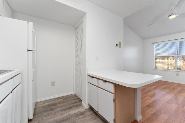 kitchen featuring kitchen peninsula, light hardwood / wood-style flooring, white cabinets, and vaulted ceiling