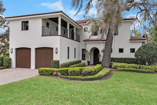 mediterranean / spanish-style home with a balcony, a front lawn, and a garage