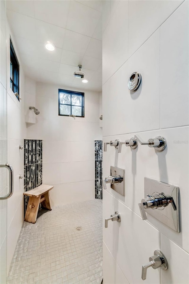 bathroom with a tile shower and tile walls