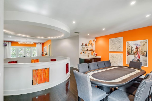 dining area with wood-type flooring, indoor bar, and a chandelier