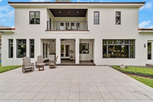 rear view of property with a patio area, a balcony, and french doors