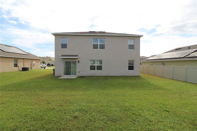 rear view of property featuring a lawn and central AC