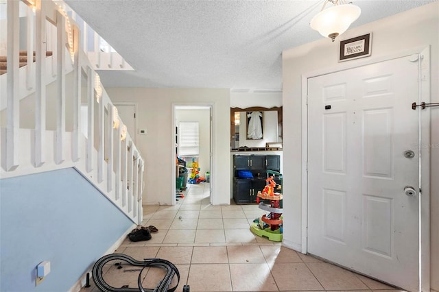 foyer entrance featuring a textured ceiling and light tile patterned flooring