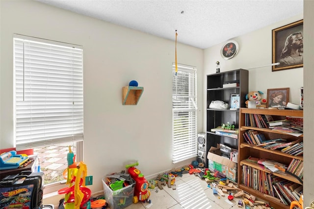 recreation room featuring tile patterned flooring, a textured ceiling, and plenty of natural light