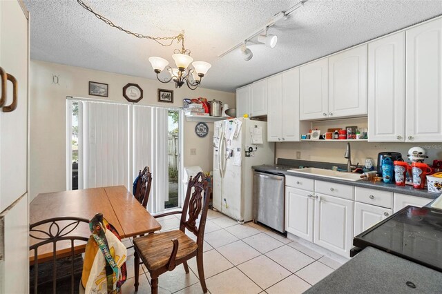 kitchen with dishwasher, sink, light tile patterned floors, white cabinetry, and a chandelier