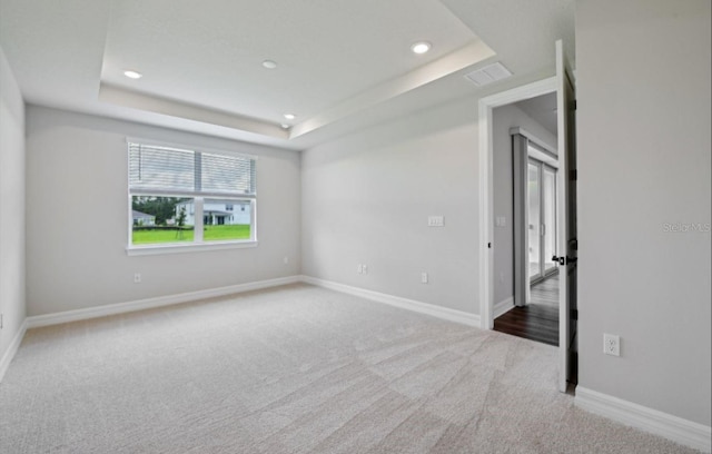 carpeted empty room with a raised ceiling