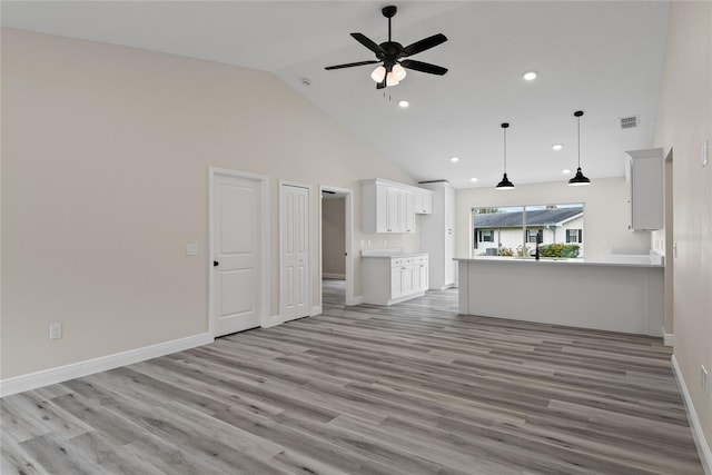 unfurnished living room with high vaulted ceiling, ceiling fan, and light wood-type flooring