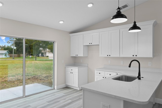 kitchen featuring pendant lighting, white cabinetry, sink, light stone counters, and kitchen peninsula