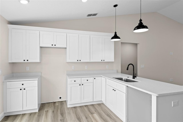 kitchen with hanging light fixtures, sink, white cabinets, and kitchen peninsula