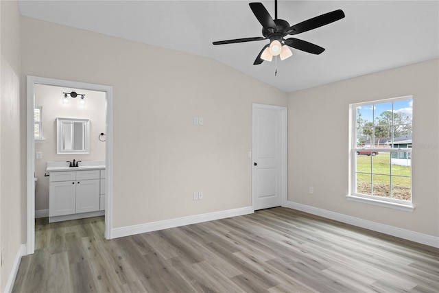 unfurnished bedroom with ensuite bathroom, sink, vaulted ceiling, light wood-type flooring, and ceiling fan