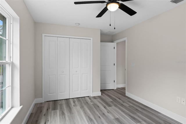 unfurnished bedroom featuring multiple windows, light hardwood / wood-style floors, a closet, and ceiling fan