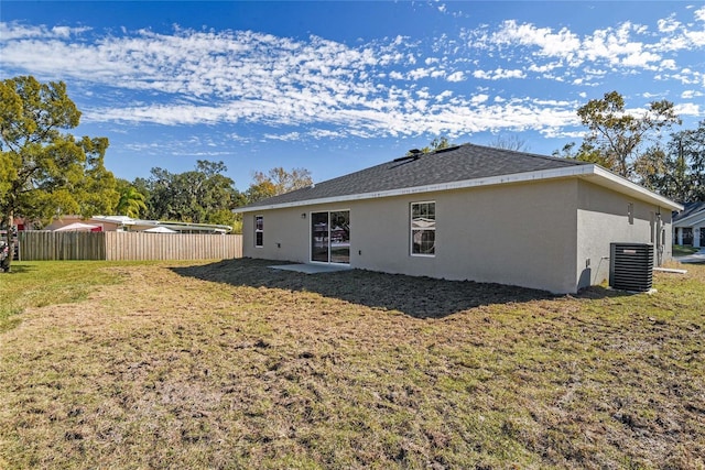 rear view of property with a yard and central air condition unit