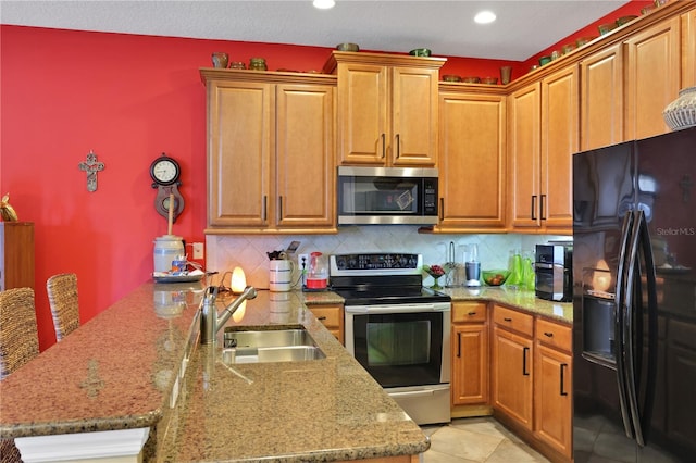 kitchen with kitchen peninsula, appliances with stainless steel finishes, tasteful backsplash, sink, and light tile patterned floors