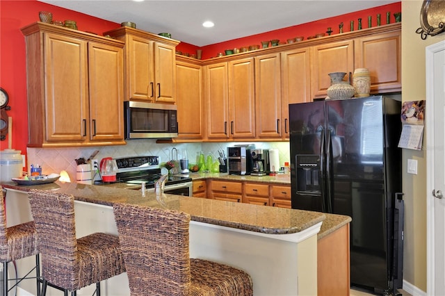 kitchen with kitchen peninsula, appliances with stainless steel finishes, backsplash, a kitchen breakfast bar, and light stone counters