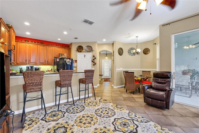 kitchen featuring ceiling fan, a kitchen breakfast bar, backsplash, kitchen peninsula, and black refrigerator