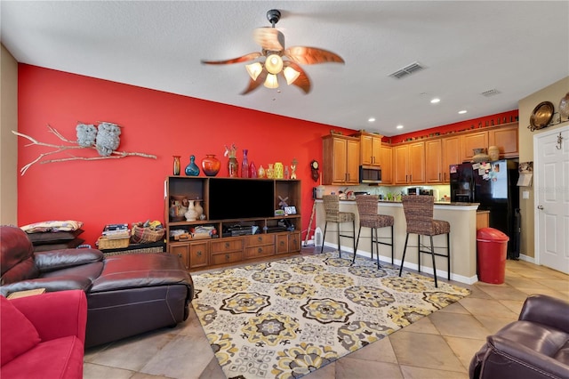 living room featuring light tile patterned floors, a textured ceiling, and ceiling fan