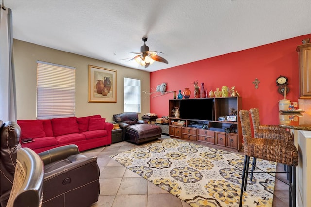 living room with ceiling fan, light tile patterned floors, and a textured ceiling