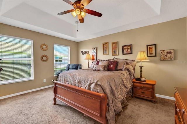 bedroom featuring ceiling fan, a raised ceiling, and light colored carpet