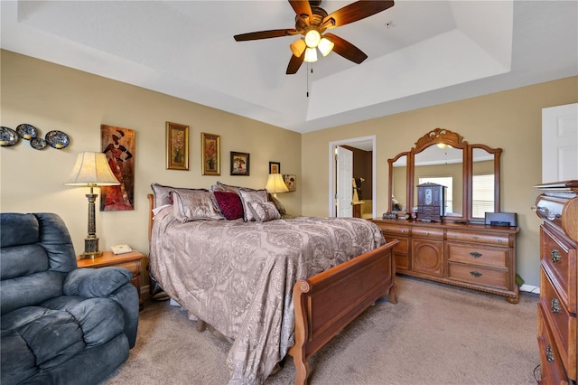 bedroom with a tray ceiling, ceiling fan, and light colored carpet