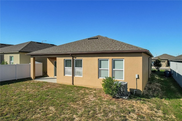 rear view of property featuring a patio, central AC, and a lawn