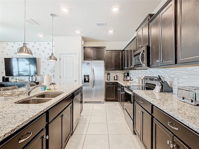 kitchen with dark brown cabinetry, sink, hanging light fixtures, stainless steel appliances, and tasteful backsplash