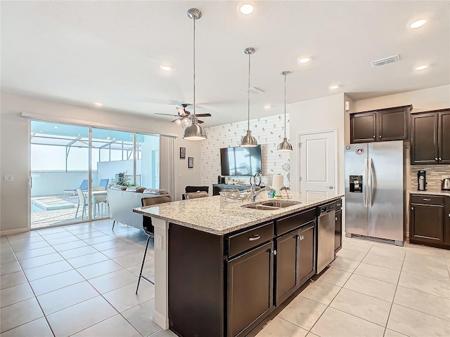 kitchen with ceiling fan, sink, stainless steel appliances, a kitchen island with sink, and light tile patterned floors